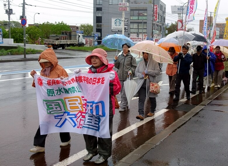 激しい雨をつき、吉岡さん（右側）を先頭に行進する平和行進清田コース